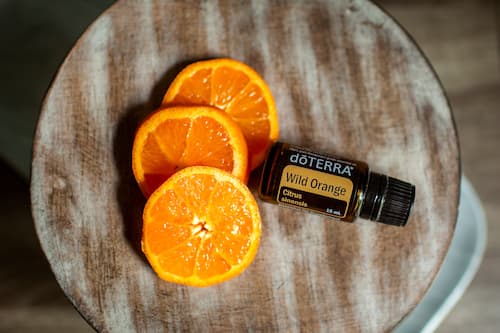 bottle of doTERRA wild orange essential oil with orange slices on wood