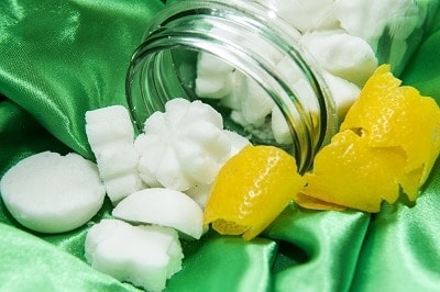 homemade dishwasher tabs in a mason jar with lemon peel and a green background