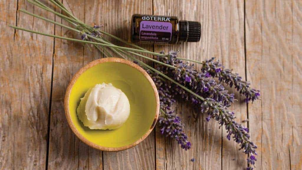 a bowl with diy cuticle cream and a bottle of  doterra lavender essential oil