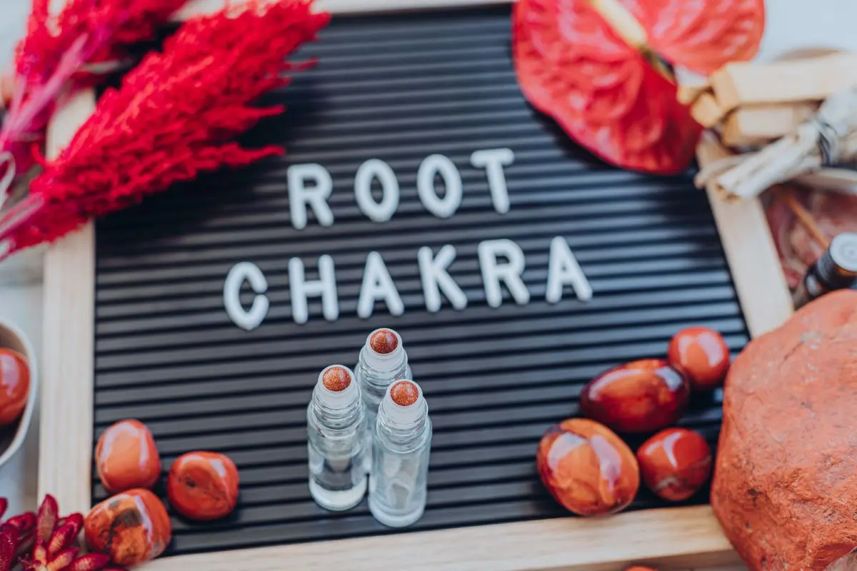 sign with the words root chakra with essential oil bottles and flowers around it