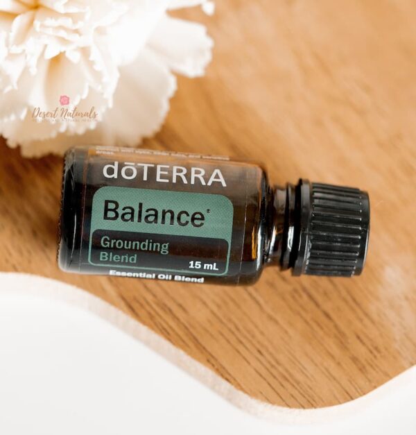 image of doterra balance grounding essential oil blend on wood with a white flower