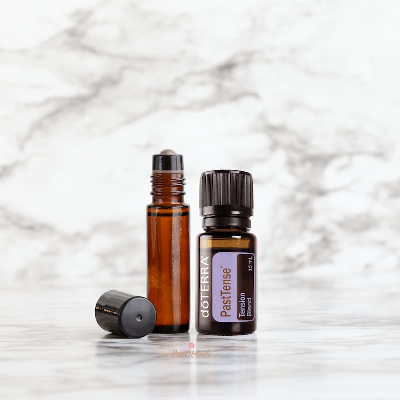 marble background with image of bottle of doterra past tense head blend with a roller