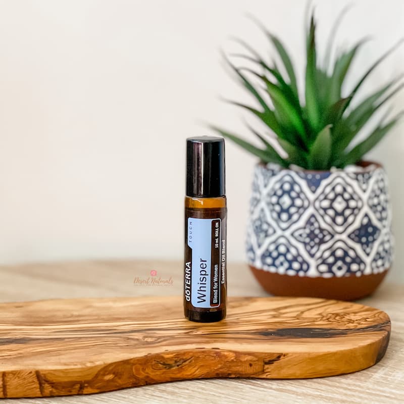 image of doterra whisper women's roller on wood and plant in background