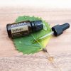 wood background with green leaf and bottle and dropper of doterra vetiver essential oil