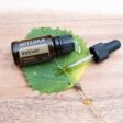 wood background with green leaf and bottle and dropper of doterra vetiver essential oil