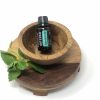 a bottle of doterra spearmint essential oil in a wooden bowl with a sprig of spearming