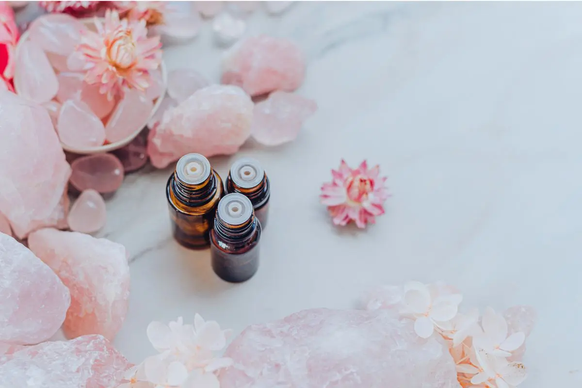 pink crystals and flowers and essential oil bottles for the crown chakra