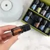 flat lay of doterra healthy start kit in the box with hand holding bottle of frankincnese essential oil