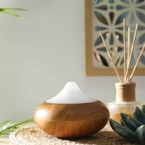 essential oil diffuser on furniture with mirror on wall and houseplant