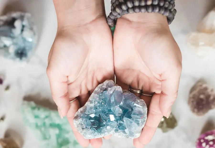 womans hands holding blue crystal