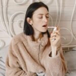 sick woman using a sore throat essential oil spray