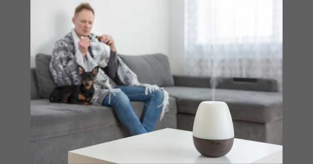 essential oil diffuser with sick man in background
