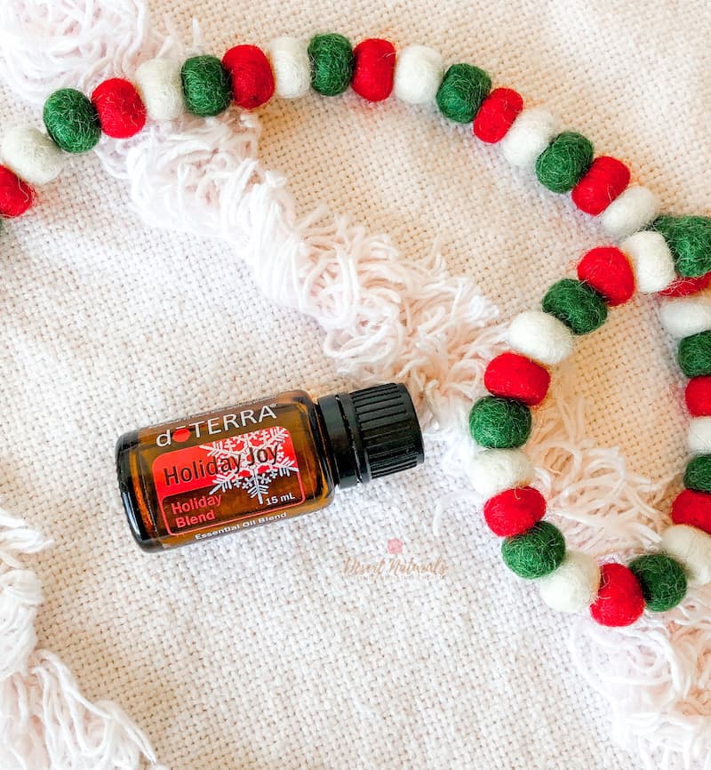 Christmas garland with a bottle of doterra Holiday Joy essential oil