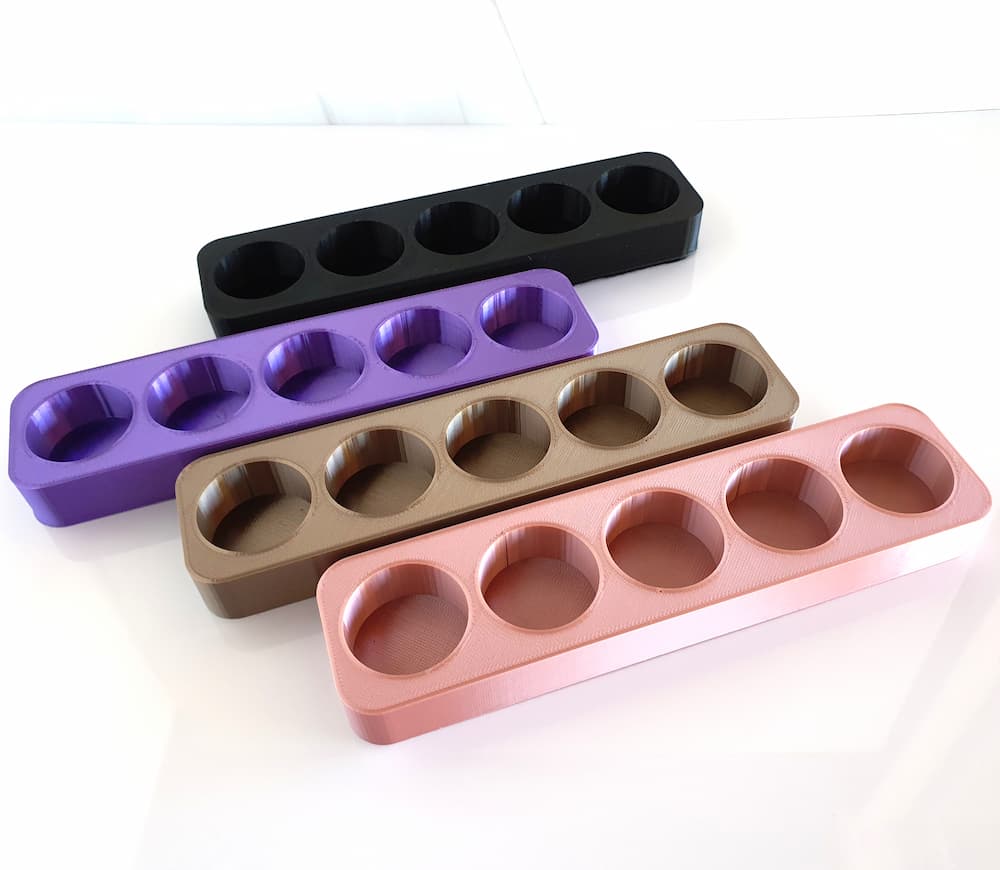 white background with photo of 3d printed essential oil stands in various colors