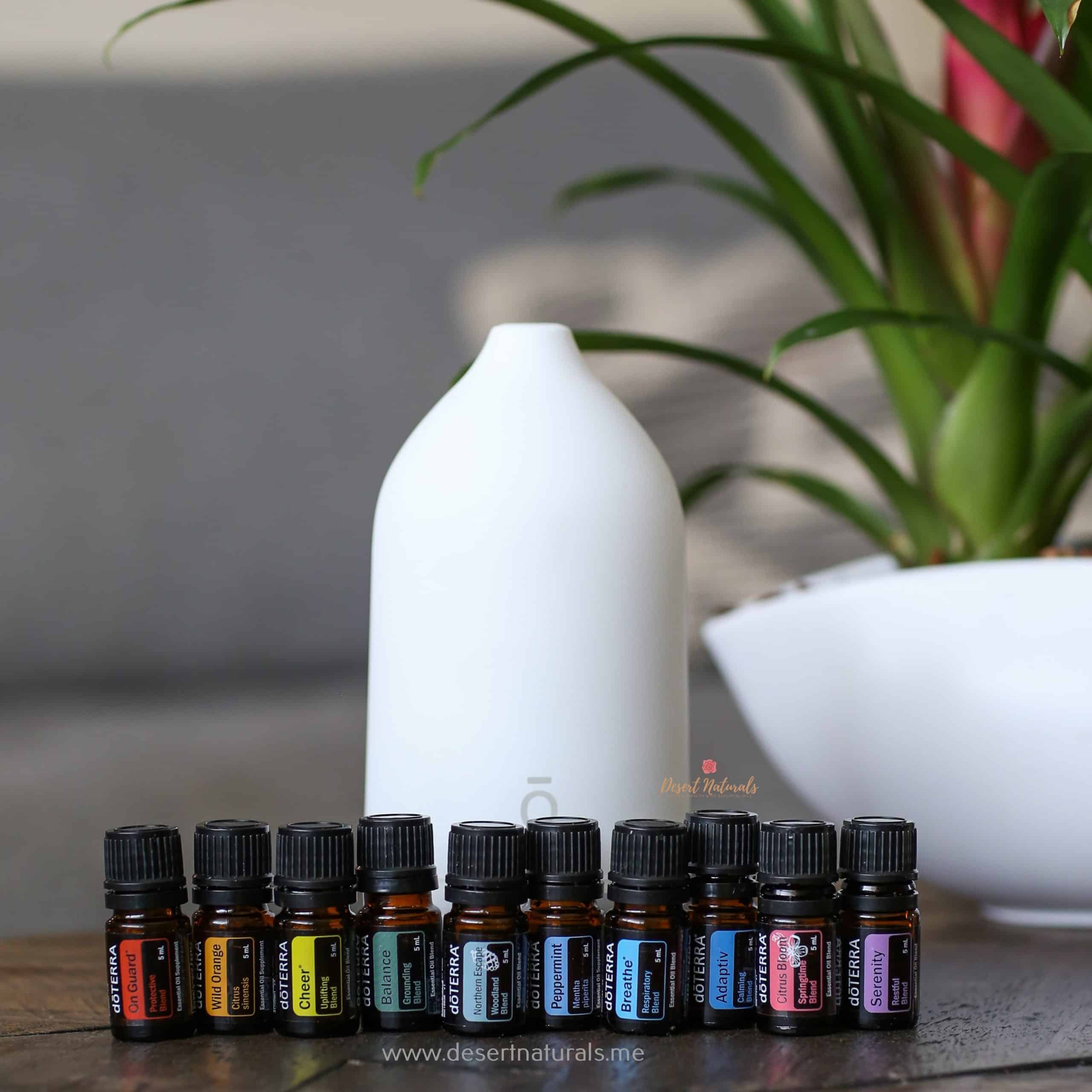 flowers in the background with doterra essential oil bottles and laluz diffuser from the aroma essentials starter kit