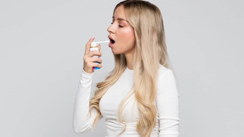 woman spraying inside her mouth with a homemade throat spray