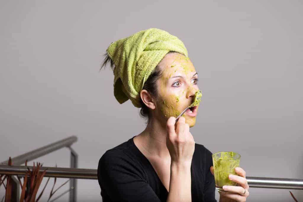 womand putting avocado on her face