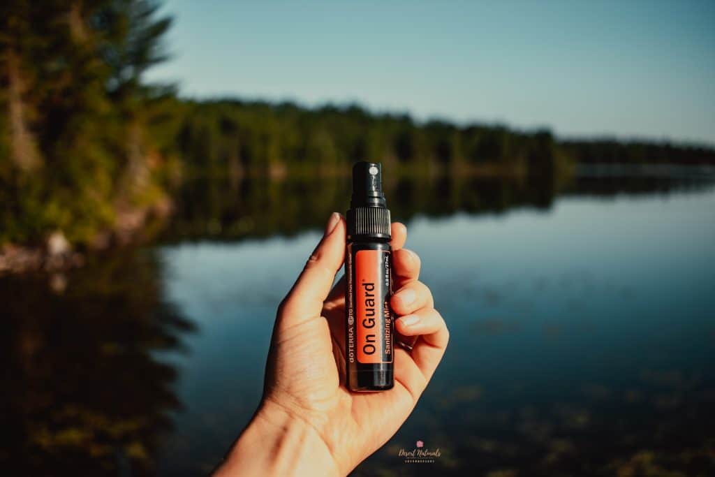 doterra on guard hand sanitizing spray with a lake in the background for camping