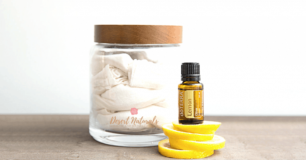jar of reusable cloth wipes for dusting with a bottle of doterra lemon essential oil on top of lemon peels