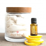 jar of reusable cloth wipes for dusting with a bottle of doterra lemon essential oil on top of lemon peels