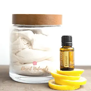 jar of reusable cloth wipes for dusting with a bottle of doterra lemon essential oil on top of lemon peels