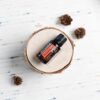bottle of doterra harvest spice on a small wood disk with small pinecones
