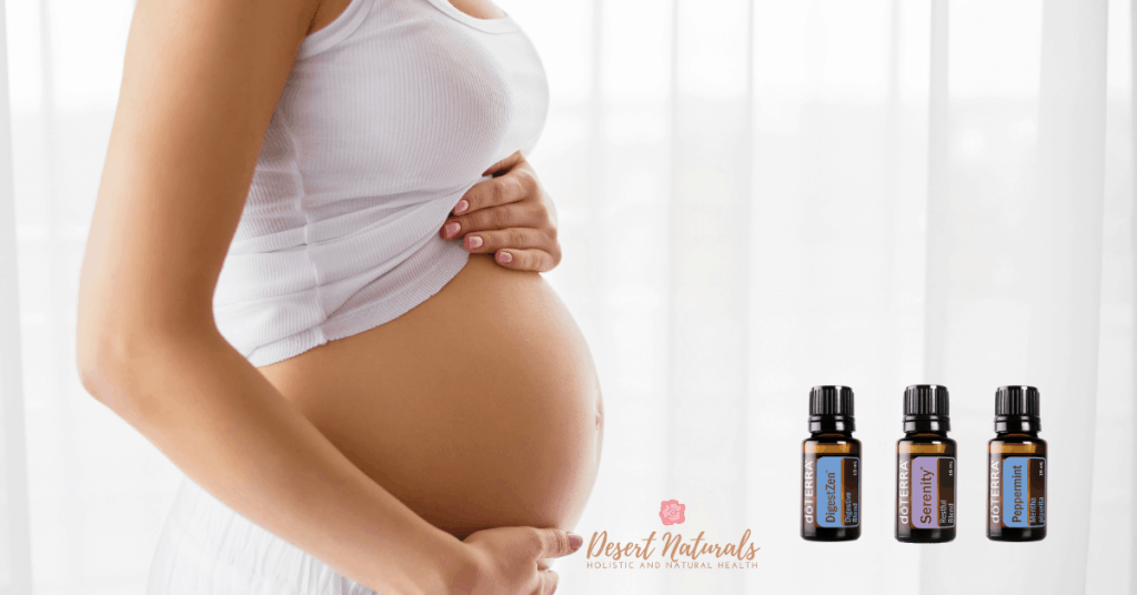 pregnanty belly on white background with some doterra essential oil bottles