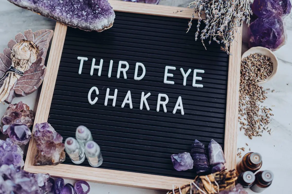 photo of sign with the words third eye chakra with crystals and essential oils around it