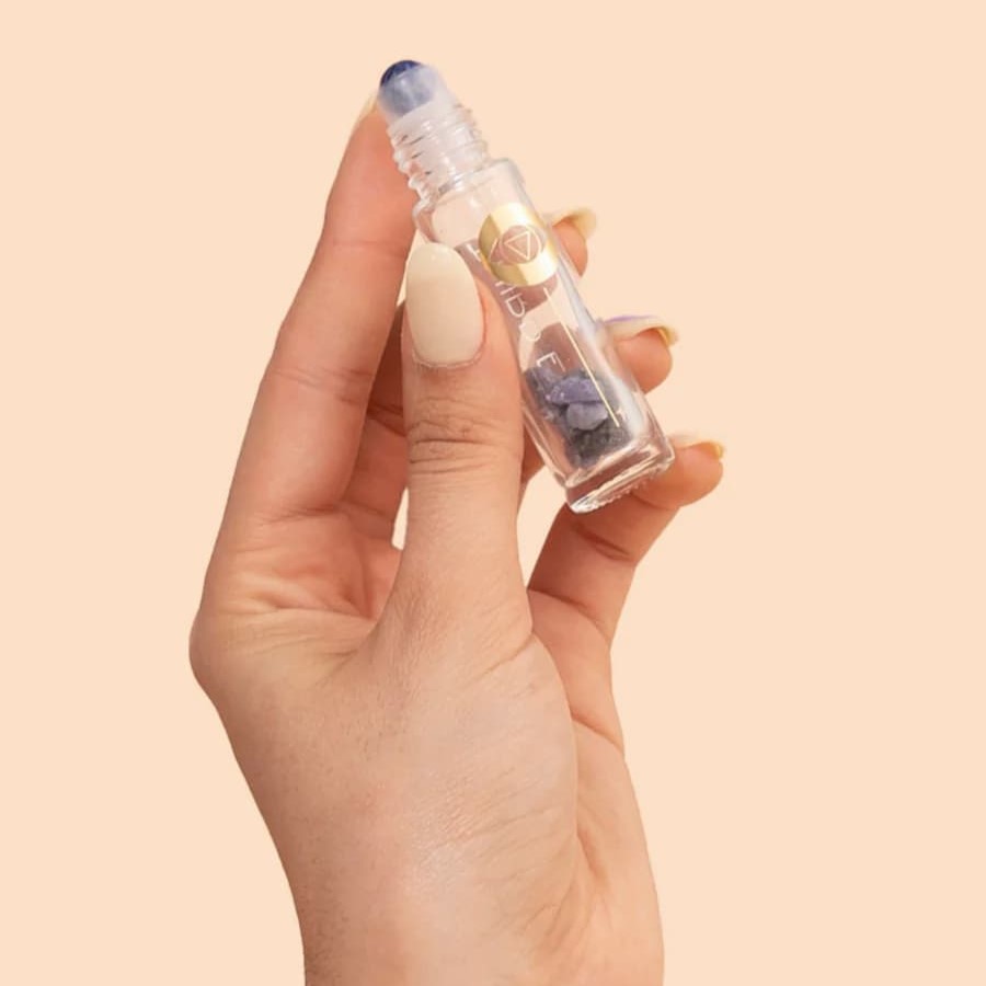 woman's hand holding a third eye chakra crystal essential oil roller