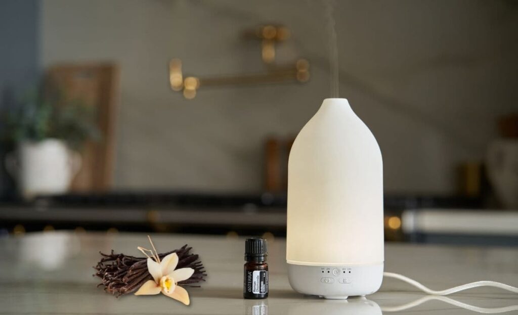 bottle of doterra vanilla essential oil, a diffuser, and vanilla beans