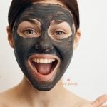 white background with woman laughing with a diy charcoal face mask on