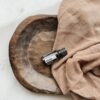 bottle of doTERRA Abode essential oil in wood bowl with towel