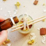 homemade candle with hand holding essential oils to add to the candle