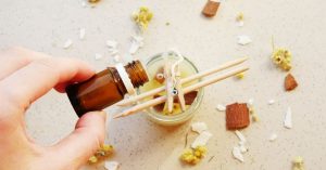 homemade candle with hand holding essential oils to add to the candle