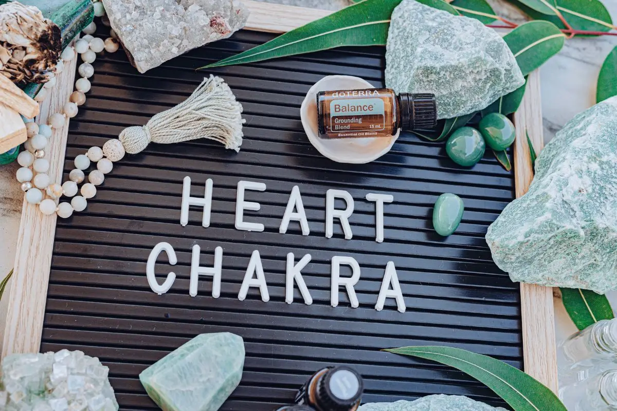 a sign with the words heart chakra and a bottle of essential oil