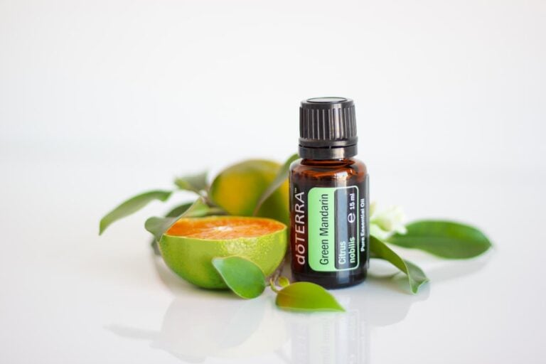 bottle of doterra green mandarin essential oil in front of a green mandarin cut open