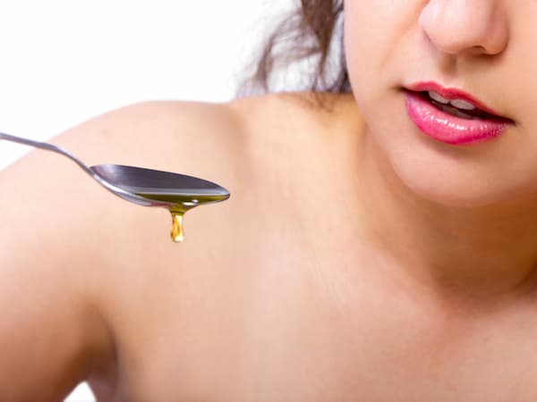 a woman holding a spoon to begin oil pulling