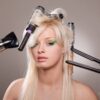 woman with hair dryer, heated hair straightener and brushes in her hair