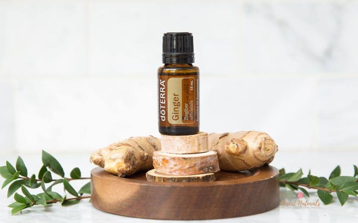 image of bottle of doterra ginger essential oil on top of fresh ginger and wood stand with plant