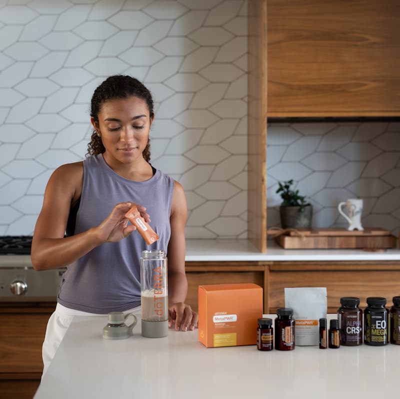 image of woman pouring doterra metapwr advantage collagen into glass of water