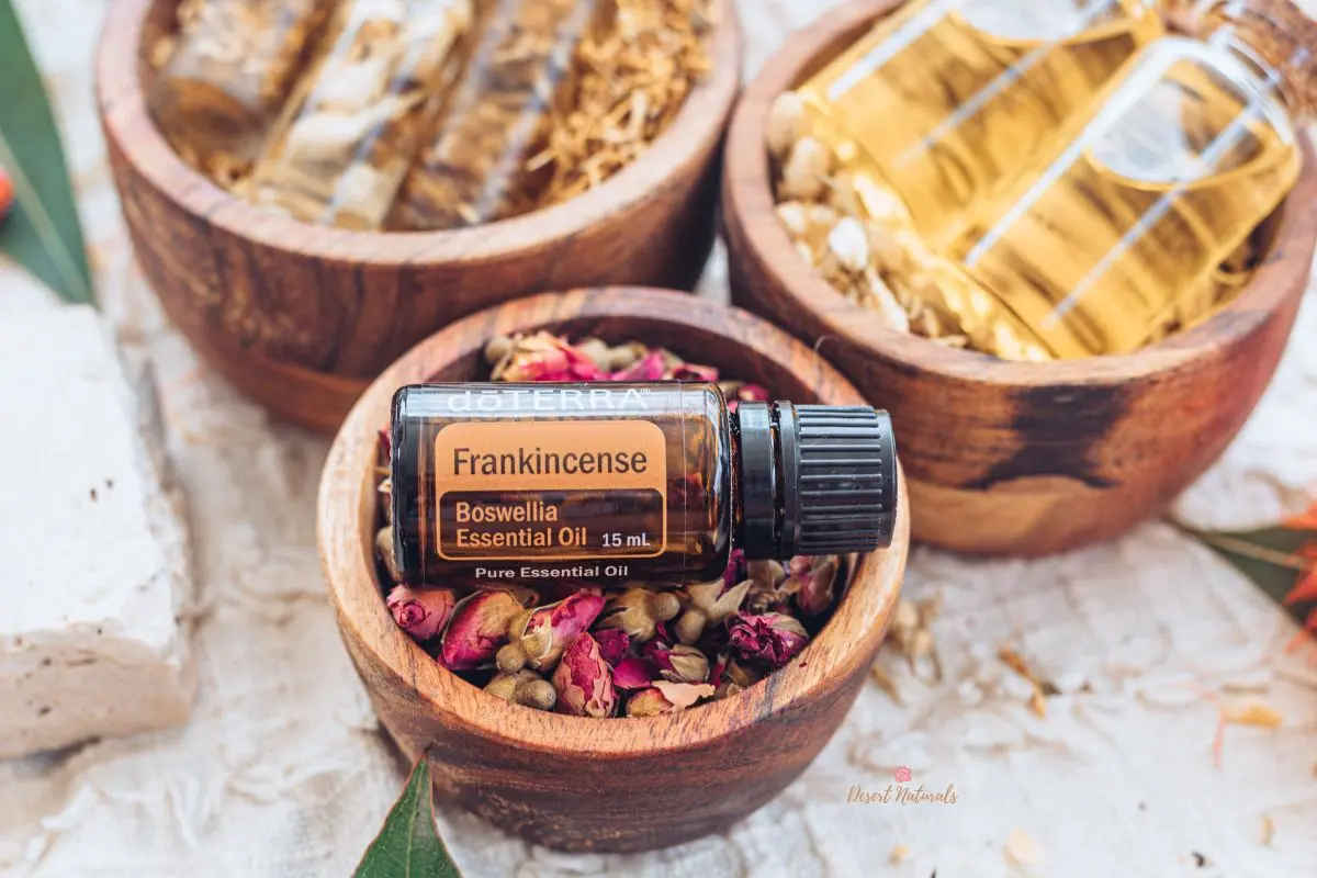 bottle of doterra frankincense essential oil in wooden bowl with dried flowers