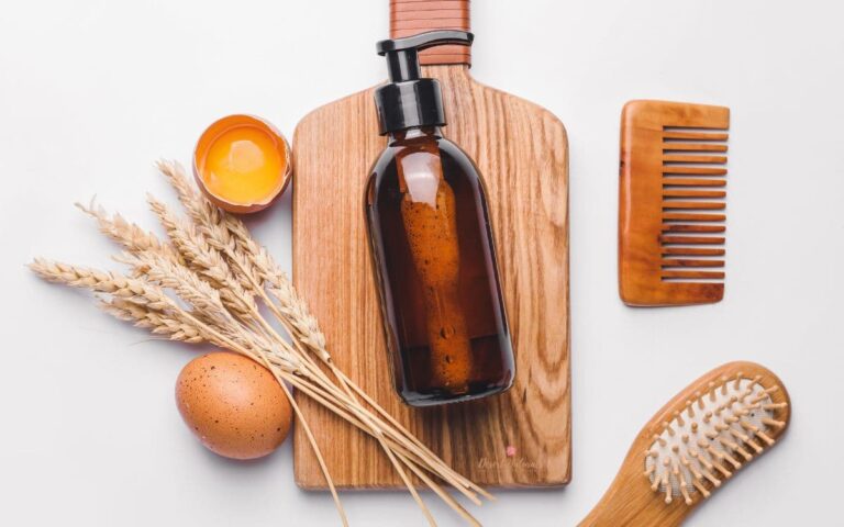 wood board with bottle of natural homemade essential oil hair product and eggs