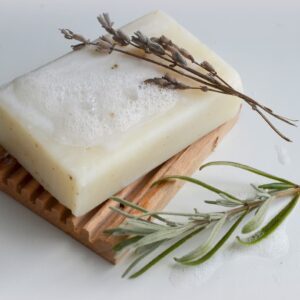 a bar of homemade essential oil soap with a sprig of lavender and rosemary