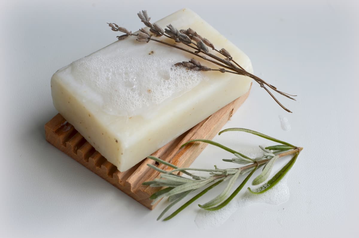 a bar of homemade essential oil soap with a sprig of lavender and rosemary