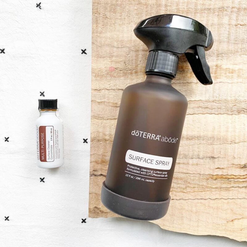 doTERRA Abode multi purpose cleaner concentrate with spray bottle photo of doTERRA multi purpose cleaner concentrate on a towel with a spray bottle on wood