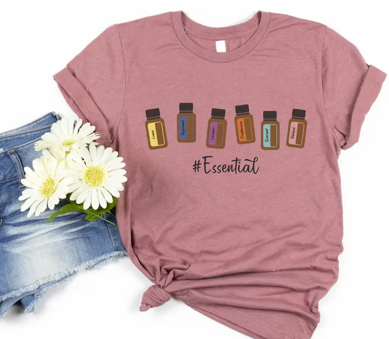essential oil bottle tshirt mockup heather mauve flatlay doterra essential oil bottle tee with denim shorts and flowers on a white background