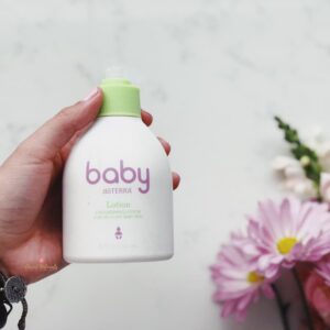 woman's hand holding doTERRA Baby Lotion with flowers