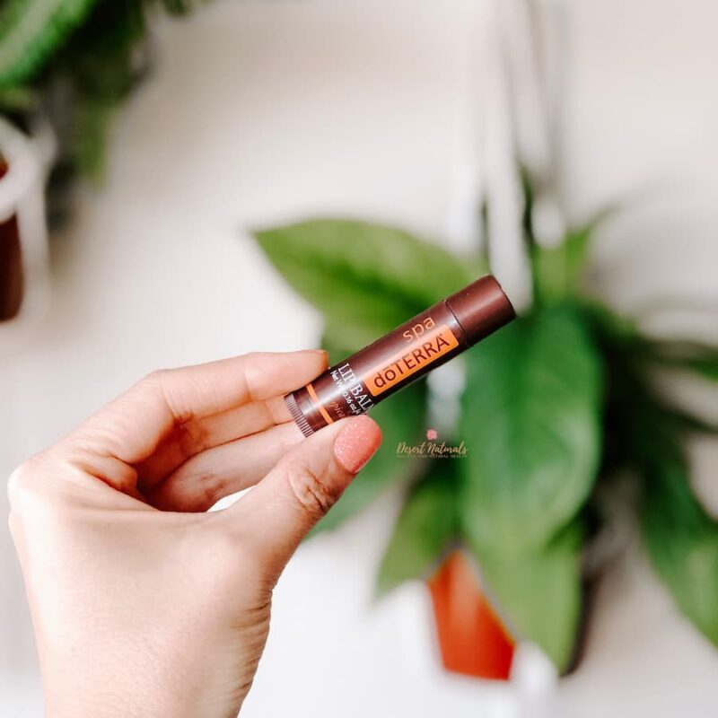 doterra Lip Balm Tropical plant woman's hands holding tube of doTERRA Tropical Lip Balm in front of a plant