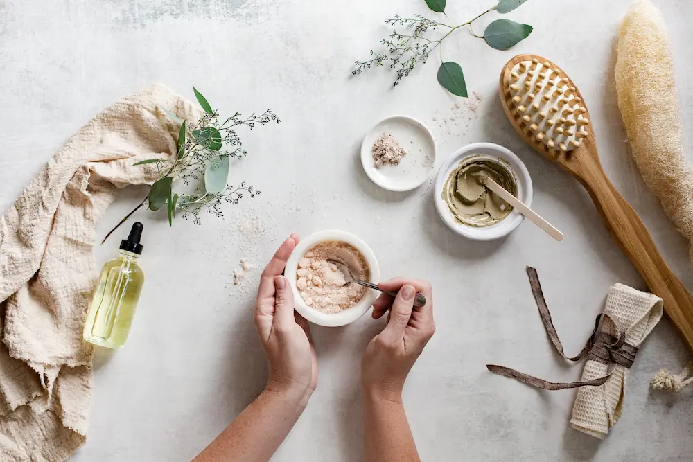 womans hands mixing diy salt scrub with essential oil