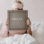 woman in bed with eye mask and relax sign for better sleep